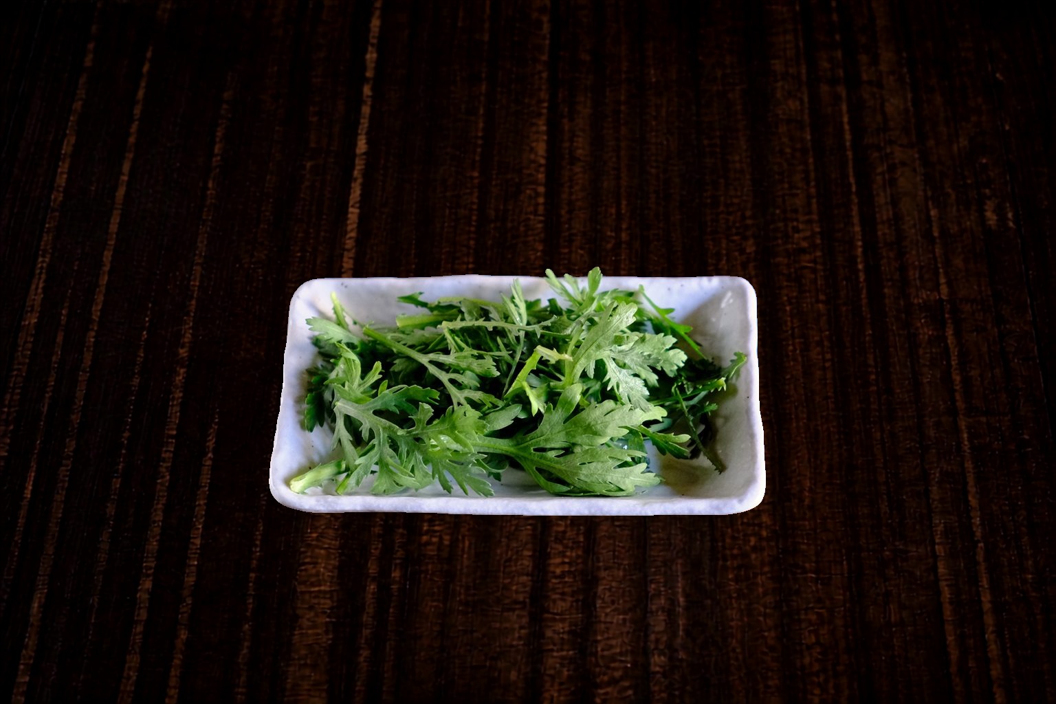 春菊 — 「着丼したら、スープが熱いうちに春菊をスープに浸して食べる」のが美味しくいただくための黄金ルールです。熱々のスープにしっかり浸すことで春菊特有のエグみが消え、ほのかな甘苦さと爽やかな香りがスープに溶け出します。深みのあるまろやかな出汁と絶妙に調和し、スープの油っぽさをすっきりと整えます。もちもちの平打ち手揉みちぢれ麺、大ぶりの極旨チャーシューとの相性も抜群です。